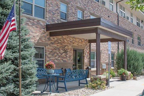 a patio with a table and benches in front of a brick building