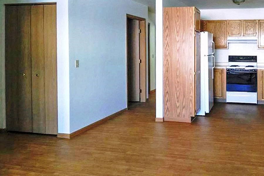 an empty kitchen with wood floors and a refrigerator