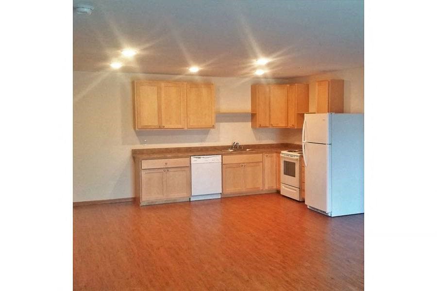 an empty kitchen with wooden cabinets and a white refrigerator