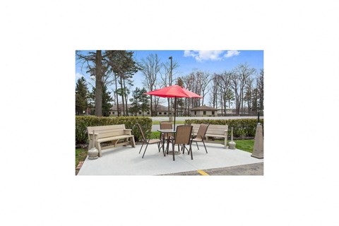a patio with tables and chairs and a red umbrella