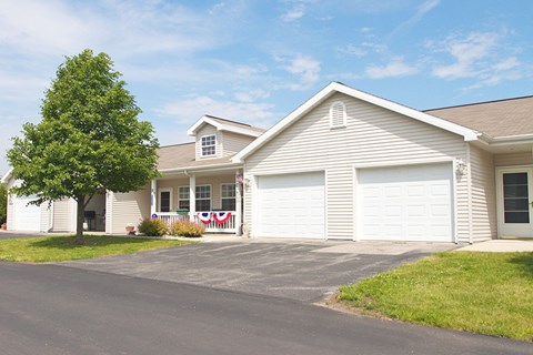A house with a garage and a tree in front.