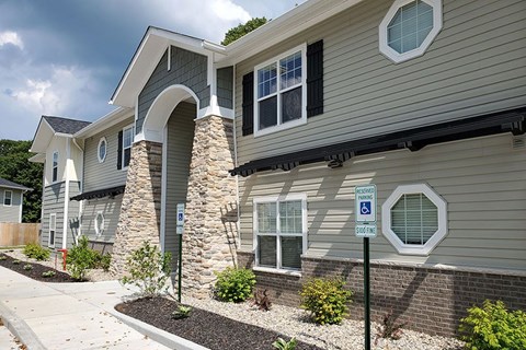 A modern house with a stone pillar and a sign indicating a handicapped parking spot.