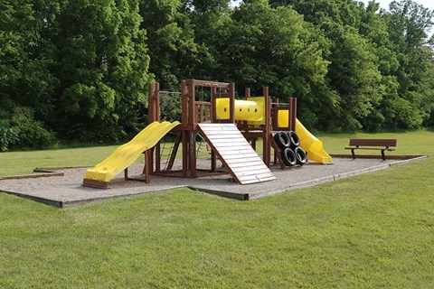 A playground with a yellow slide and a wooden structure.