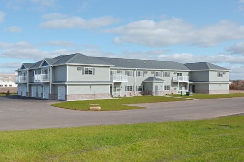 A large grey building with a parking lot in front.