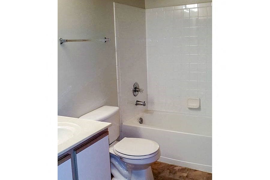 A white toilet sits in a bathroom next to a white sink.