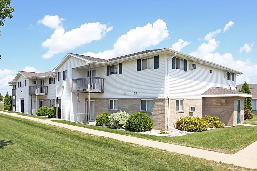 A row of houses with green lawns and white siding.