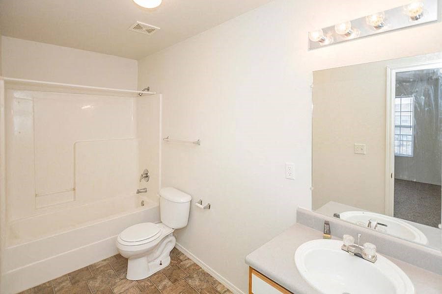 A white toilet sits in a bathroom next to a sink.