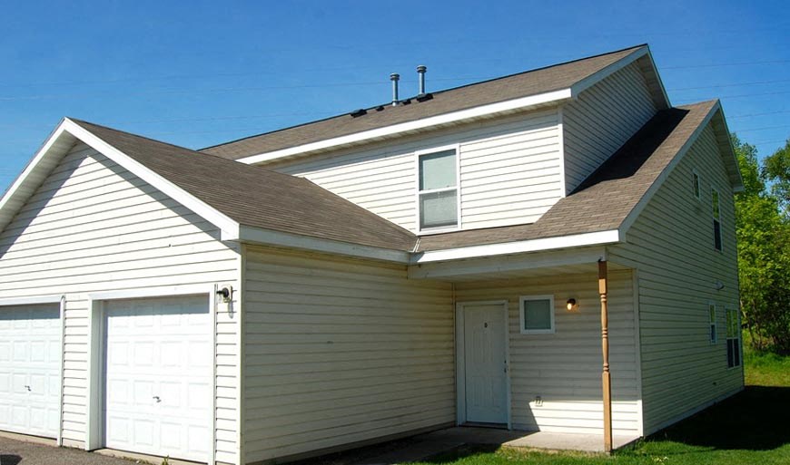 A two-story house with a white exterior and a brown roof.