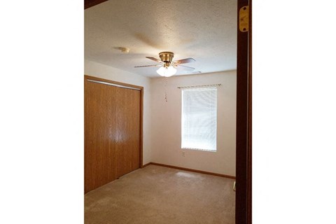 A room with a ceiling fan and a window.