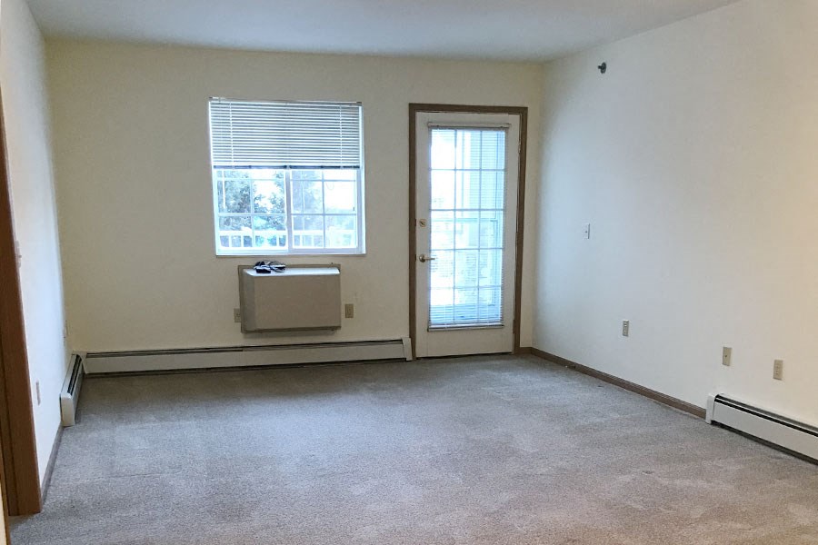 an empty living room with a door and a window