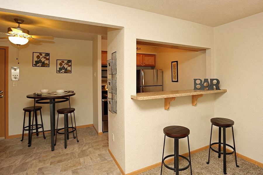 a living room with a bar and a kitchen with stools
