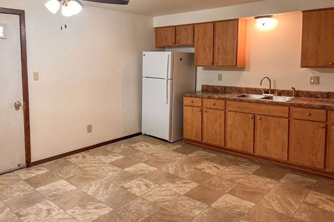 A kitchen with a white refrigerator and wooden cabinets.
