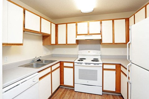 A kitchen with white appliances and wooden cabinets.