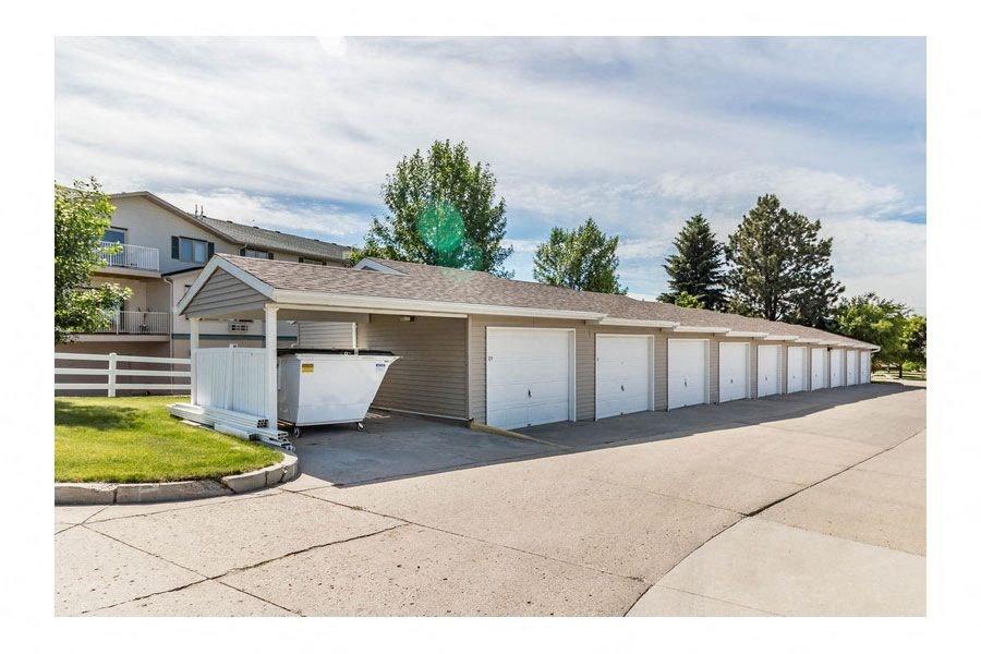 a row of white garages with a house in the background