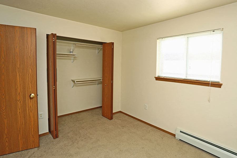 an empty room with a closet and a window