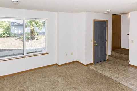 an empty living room with a blue door and a window