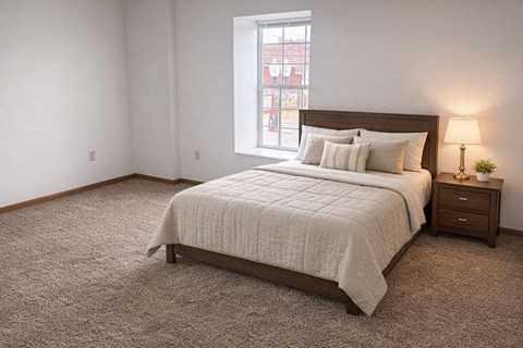 A bedroom with a bed, nightstand, and window.