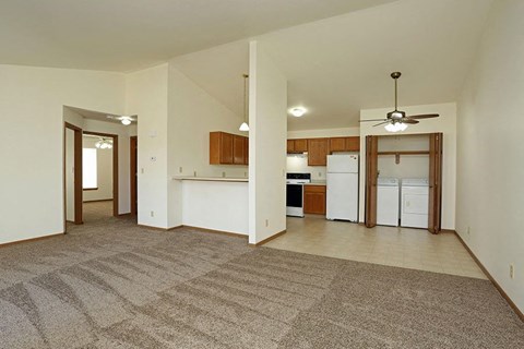 an empty living room and kitchen with a ceiling fan