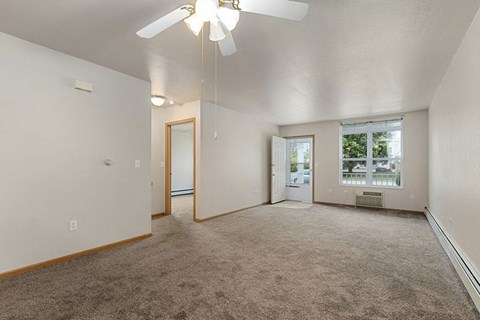 an empty living room with a ceiling fan and a window