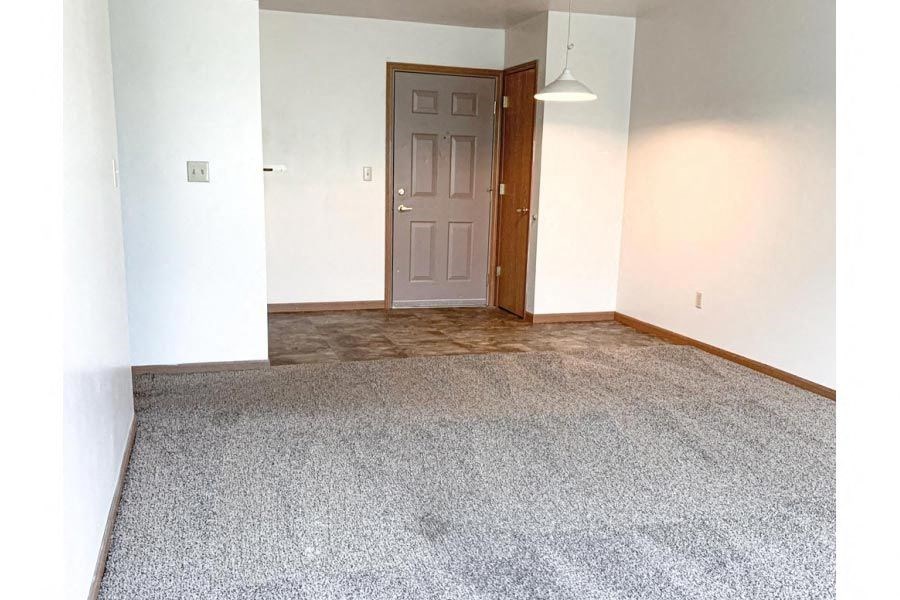 an empty room with a door and a carpet floor