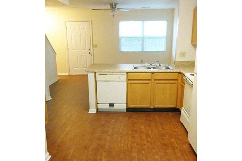 an empty kitchen with wooden floors and a sink