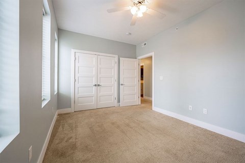 A room with a carpeted floor and a ceiling fan.