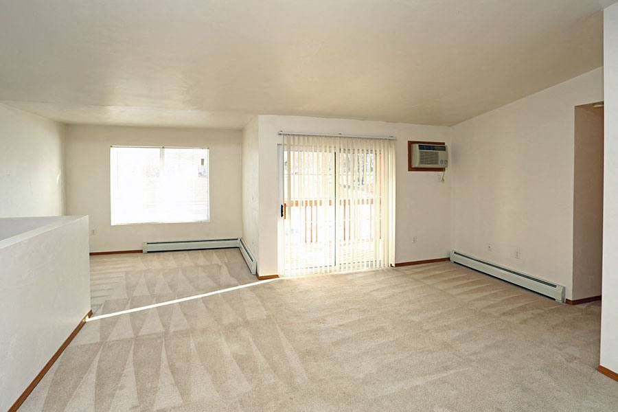 an empty living room with a door and a window