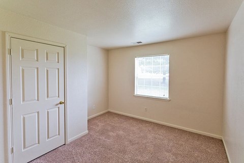 an empty room with a white door and a window