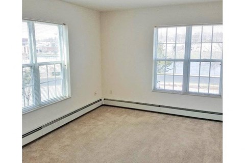 an empty room with two windows and a carpet
