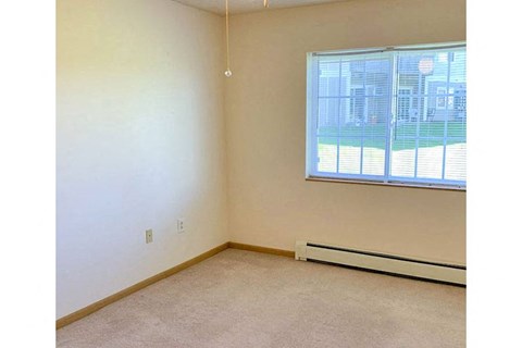an empty room with a window and a carpet