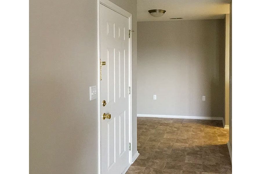 A white door with a gold handle is in a room with a tiled floor.