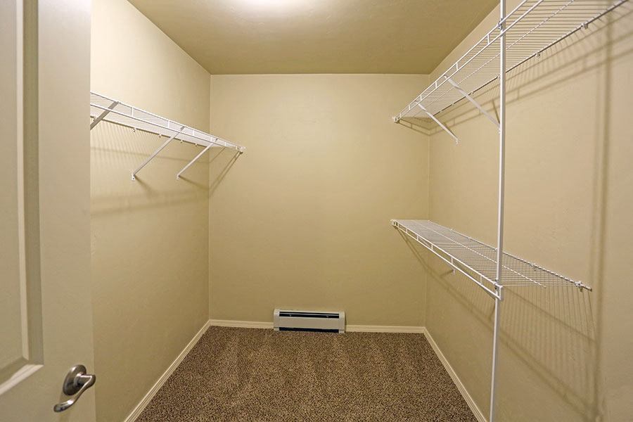 a walk in closet with two shelves and a heater