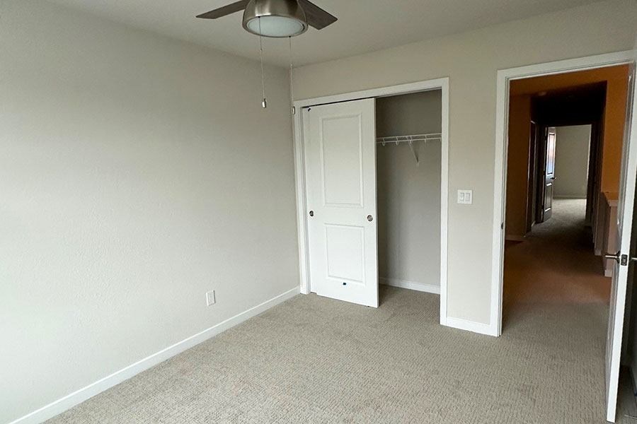 A room with a ceiling fan and carpeted floor.