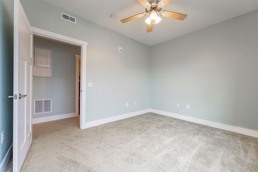 A room with a ceiling fan and carpeted floor.