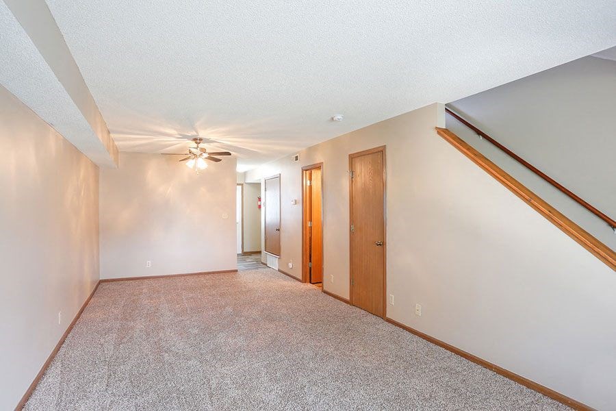 a empty living room with a ceiling fan and a hallway