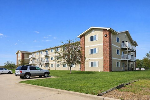A two-story apartment building with a car parked in front.