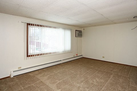 A room with a window covered by blinds and a picture hanging on the wall.