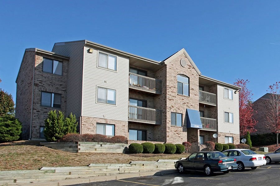 A modern apartment building with cars parked in front.