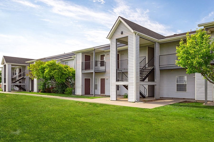 A row of white apartment buildings with green lawns in front.