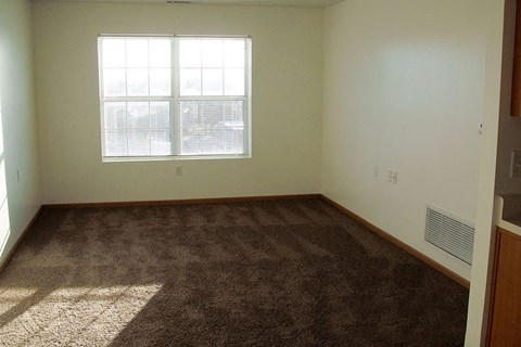 A room with a carpeted floor and a window.