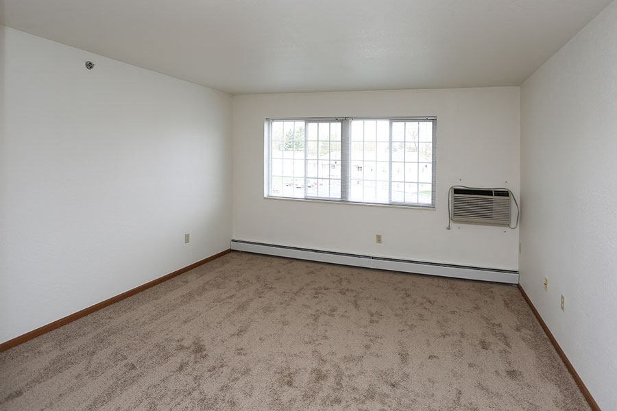 an empty living room with a window and carpet