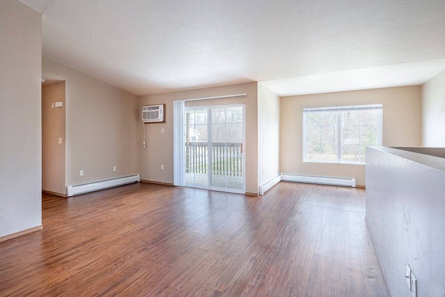 A room with wooden floors and a sliding glass door leading to a balcony.