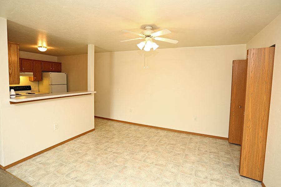 an empty living room and kitchen with a ceiling fan