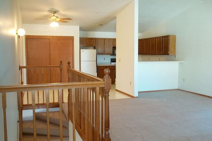 an empty living room and kitchen with a staircase