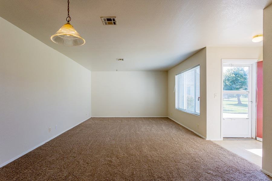 an empty living room with a door to a patio