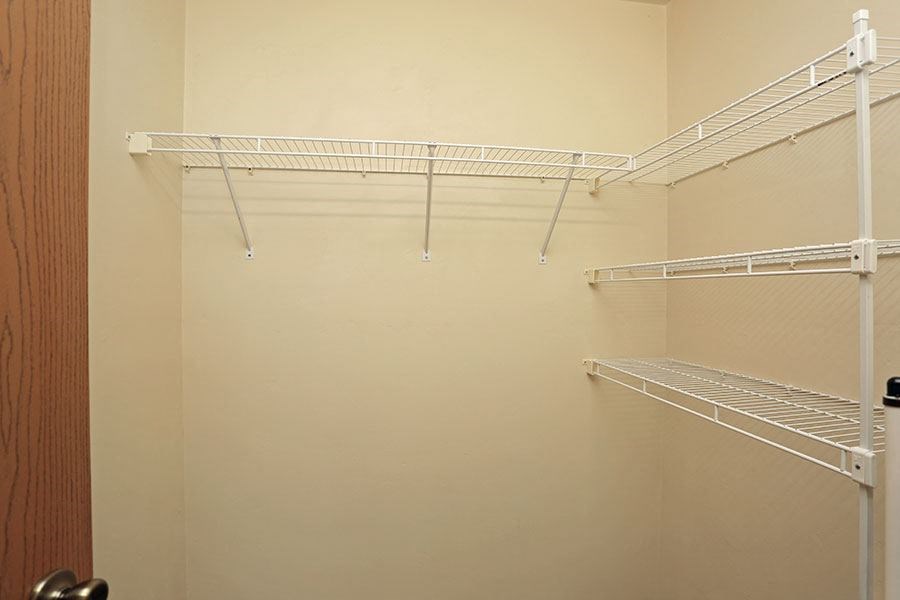 a walk in closet with empty shelves and a door