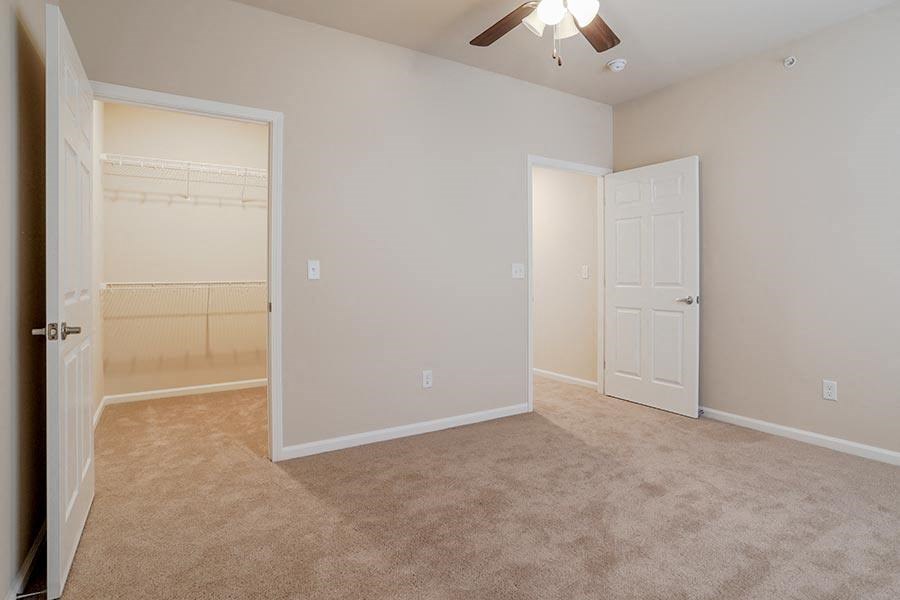 an empty bedroom with a closet and a ceiling fan