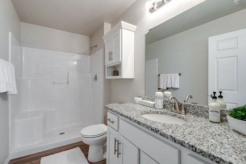 A white bathroom with a marble counter top and a white toilet.