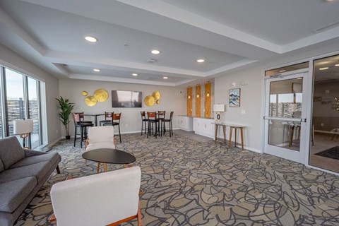 A living room with a grey sofa, a round table, and a patterned carpet.