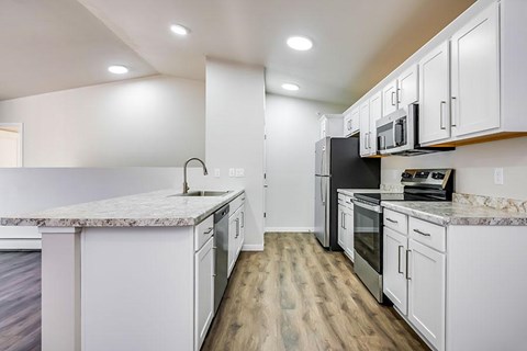 A kitchen with white cabinets and a marble countertop.